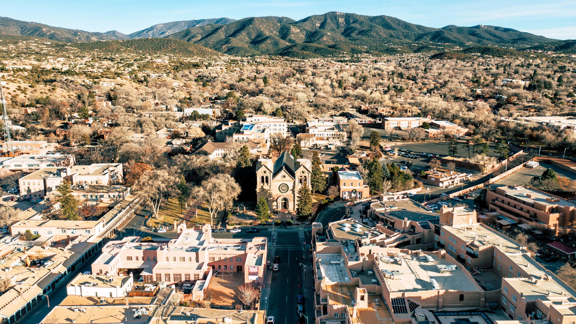 an aerial view of downtown santa fe on a sunny day with the mountains in the background