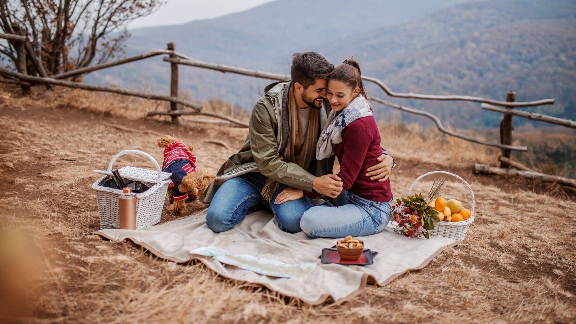 a couple is having an autumn picnic with their dog