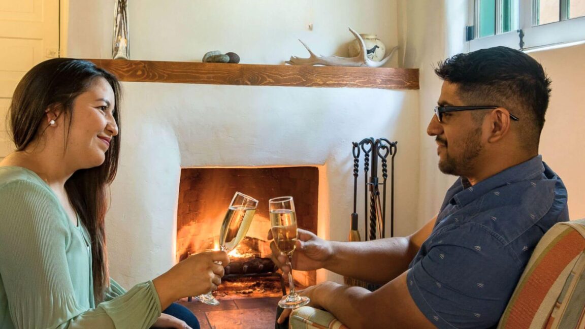 couple toasting champagne in front of kiva fireplace at inn of the turquoise bear