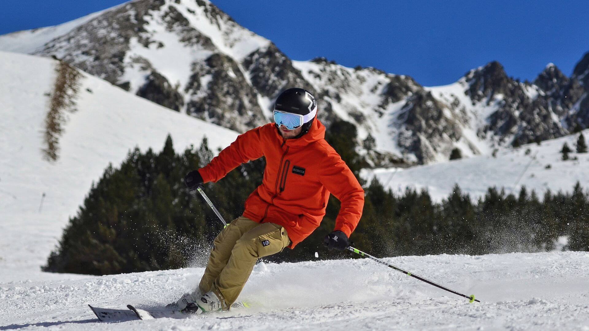 man in orange jacket skiing in mountains