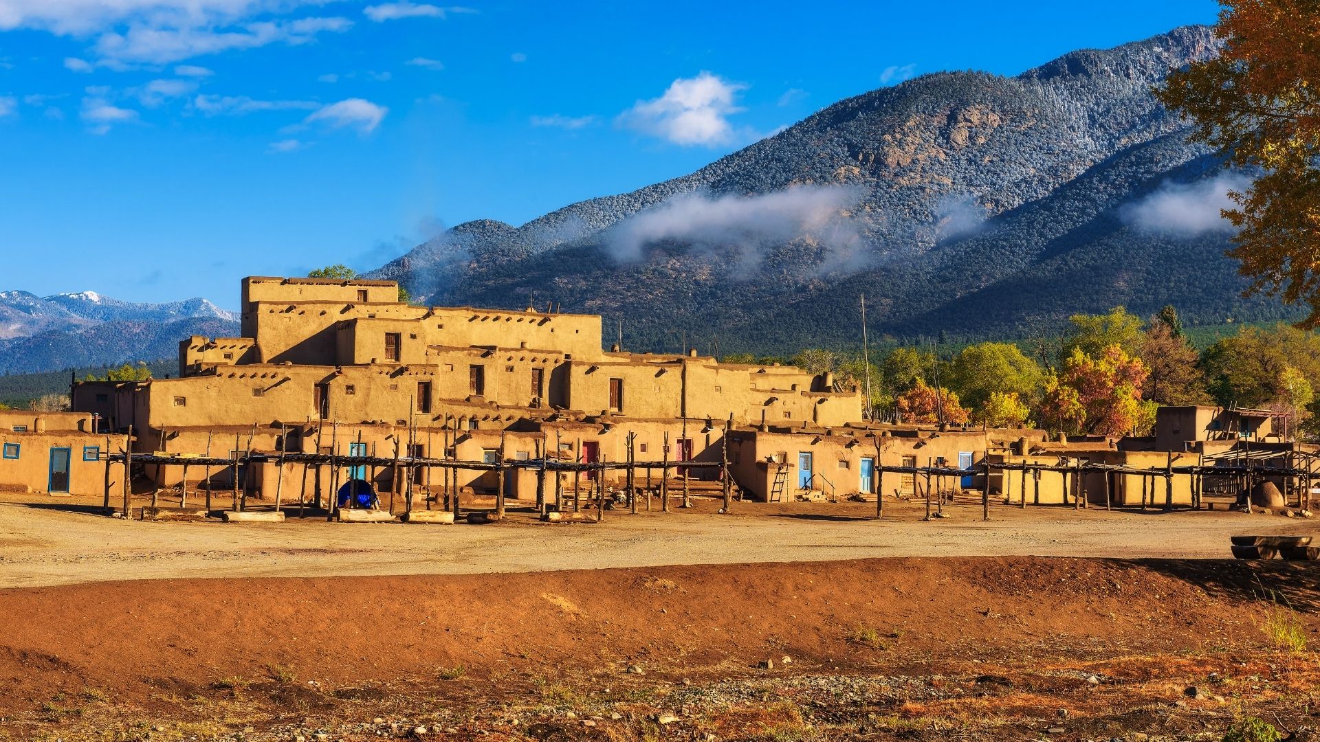 the multi-level adobe building of the taos pueblo with mountains in the background