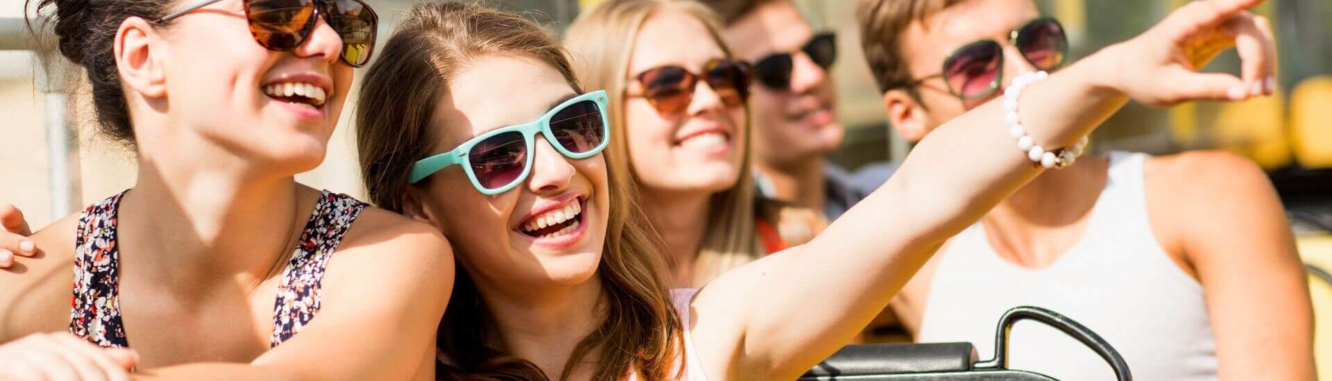 group of happy friends wearing sunglasses on trolley tour